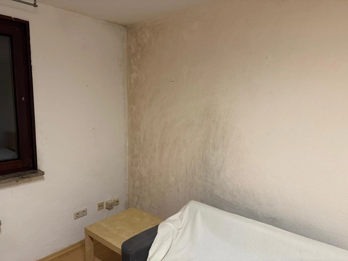 Schimmelbefall an Schlafzimmerwand vor der Sanierung